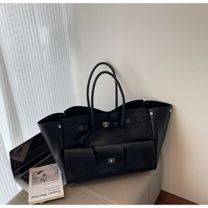Close-up of black leather tote bag with silver buckles and studs in an office setting