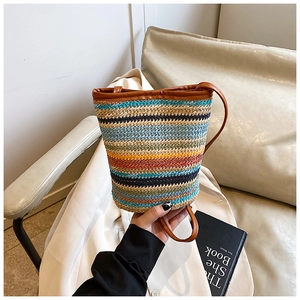 Detail of colorful striped woven bucket bag with brown leather strap and trim finish