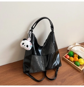 Gros plan d'un sac cabas noir brillant multifonctionnel avec breloque panda sur bois
