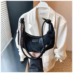 Black crescent hobo bag detail with brand tag, pink scarf and heart pendant accessory