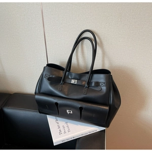 Detail of black leather tote bag featuring a silver metal twist lock and exterior pocket