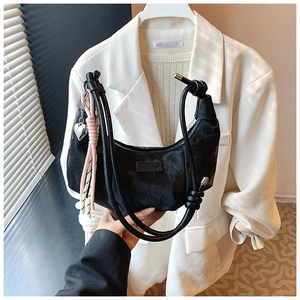 Detail of black crescent hobo bag with knotted rope handle and heart pendant accessory