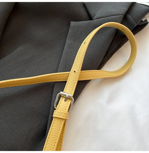 Detail of yellow lychee leather strap with silver metal buckle and adjustment holes