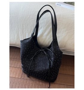 Detail of black polka dot fabric tote bag with elegant bow tie on wooden floor