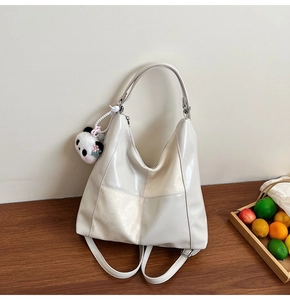 Vue détaillée du sac hobo en cuir blanc crème avec coutures croisées et breloque panda