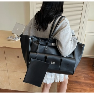 Detail of black large capacity tote bag with metal twist lock and matching small pouch