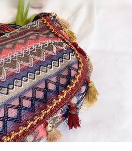 Detailed close-up of bohemian woven embroidery and bicolor tassels on a textured shoulder bag
