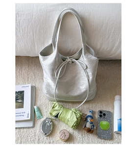 Detail of light grey floral textured tote bag with drawstring and satin finish