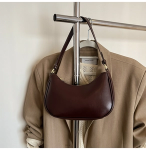 Detail of a dark brown crescent underarm bag in glossy leather on a hanger