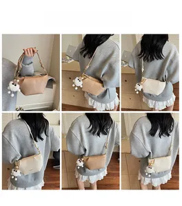 Modèle portant un sac à bandoulière beige minimaliste avec pendentif en peluche