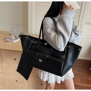 Detail of a black leather tote bag with functional pockets and a small zip pouch