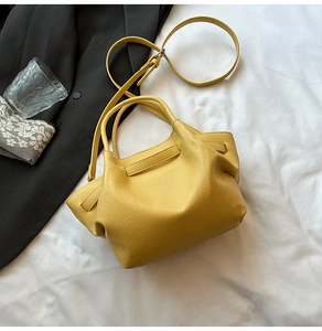 Detailed view of yellow lychee textured bucket bag with metal hardware and top handle