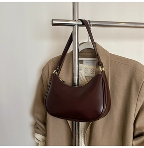 Detail of dark brown crescent hobo bag with gold hardware on a display hanger