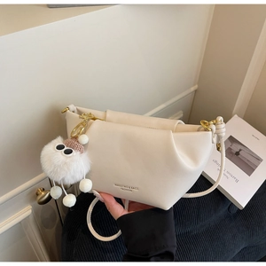 Détail du sac à main crème en cuir litchi avec pendentif monstre en peluche