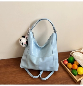 Détail du sac fourre-tout bleu clair texturé avec fermeture éclair et pendentif panda