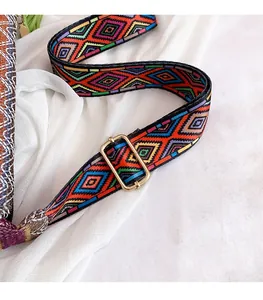 Close-up of colorful ethnic geometric woven strap with golden metal buckle on fabric