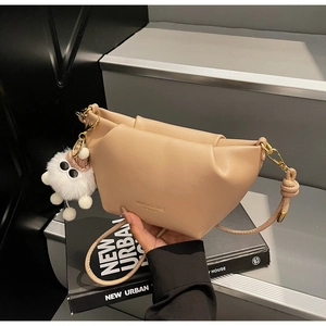 Gros plan du sac à main plissé kaki avec fermeture dorée et pendentif en peluche