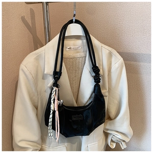 Detail of black dumpling bag with rope handle, knot design and heart pendant charm