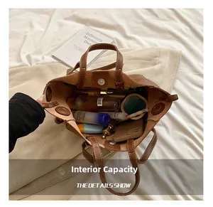Spacious interior of brown leather tote bag showing makeup, phone, and magnetic closure