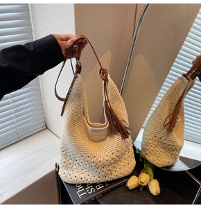 Detail of hand-woven cream hobo bag with brown leather strap and decorative tassels