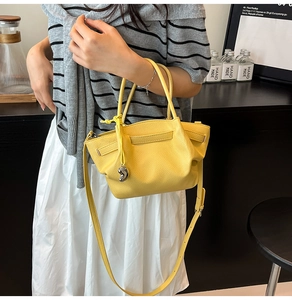 Detail of yellow lychee texture leather bucket bag with silver heart charm and shoulder strap