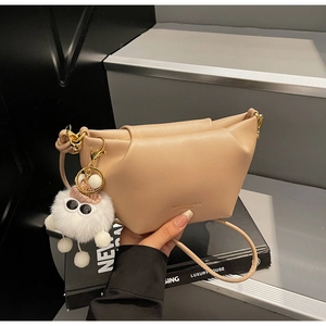 Détail d'un sac dumpling plissé kaki avec un charmant porte-clés monstre en peluche