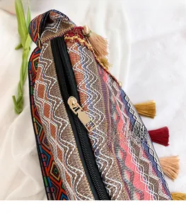 Detailed close-up of woven geometric patterns and gold zipper on ethnic tassel bag
