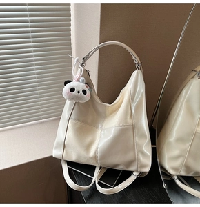 Détail du sac fourre-tout en cuir verni crème avec breloque panda et boucles métalliques