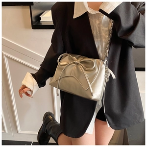 Detail of silver ballet-style crossbody bag featuring a large bow and pearl chain charm