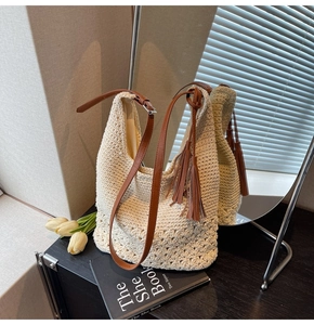 Detail of woven beige tote bag with brown leather straps and stylish tassel charm