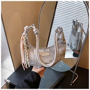 Detail of silver crescent bag with metal logo, woven handle and rope charm decoration