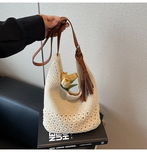 Close-up of cream woven bag with hollow floral lace pattern and brown leather straps