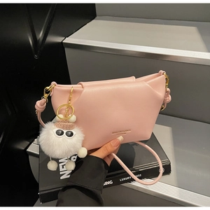 Sac rose avec logo doré, fermoir métallique et détail de pendentif monstre en peluche