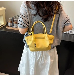 Detailed view of yellow lychee leather bucket bag showing soft texture and metal pendant