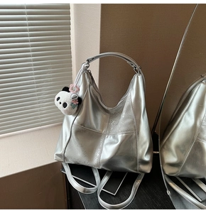 Détail du sac hobo argenté métallisé avec coutures croisées et charm panda en peluche
