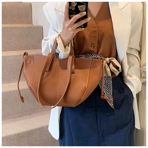 Brown lychee texture tote bag with drawstring details shown in a lifestyle street setting