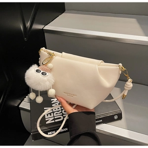 Détail du sac à main plissé blanc crème avec charm pompon et lettrage doré élégant