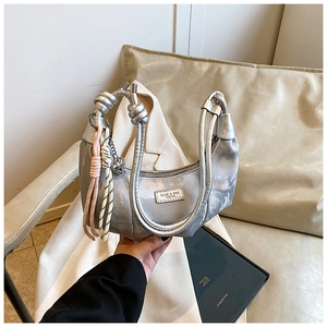 Detail of silver metallic handbag featuring a unique knotted handle and woven cord accents