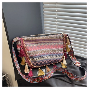 Macro detail of Bohemian woven crossbody bag featuring colorful tassels and ethnic patterns