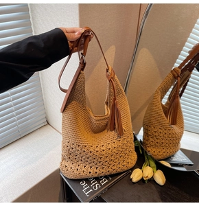 Detail of woven straw tote bag with brown leather strap and elegant tassel charm