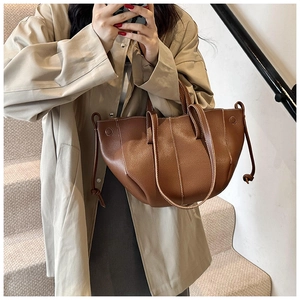 Detail of a brown lychee-textured leather tote bag with elegant white contrast stitching