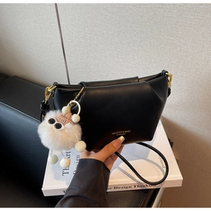 Détail d'un sac à bandoulière en cuir plissé noir avec un pendentif monstre blanc
