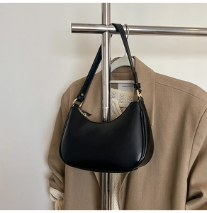 Detailed close-up of a black crescent underarm bag with gold metal hardware and buckle