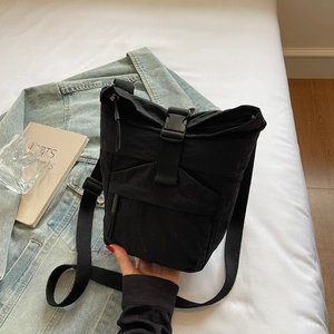 Détail d'un sac bandoulière en toile noire avec fermeture à boucle et fermetures éclair