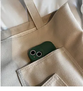 Close-up of a durable front pocket on an off-white canvas tote bag with a phone inside