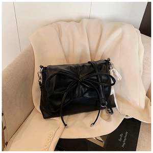 Detailed close-up of a black ballet-style shoulder bag with a large decorative bow