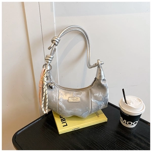 Silver crescent dumpling bag with knotted handle and heart charm on a yellow book