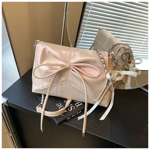 Close-up of cream shoulder bag with large bow detail and silver chain strap