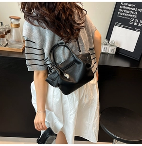 Close-up of black lychee texture leather bucket bag with silver heart charm on model