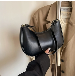 Detailed close-up of a black crescent hobo bag with gold zipper and adjustable strap